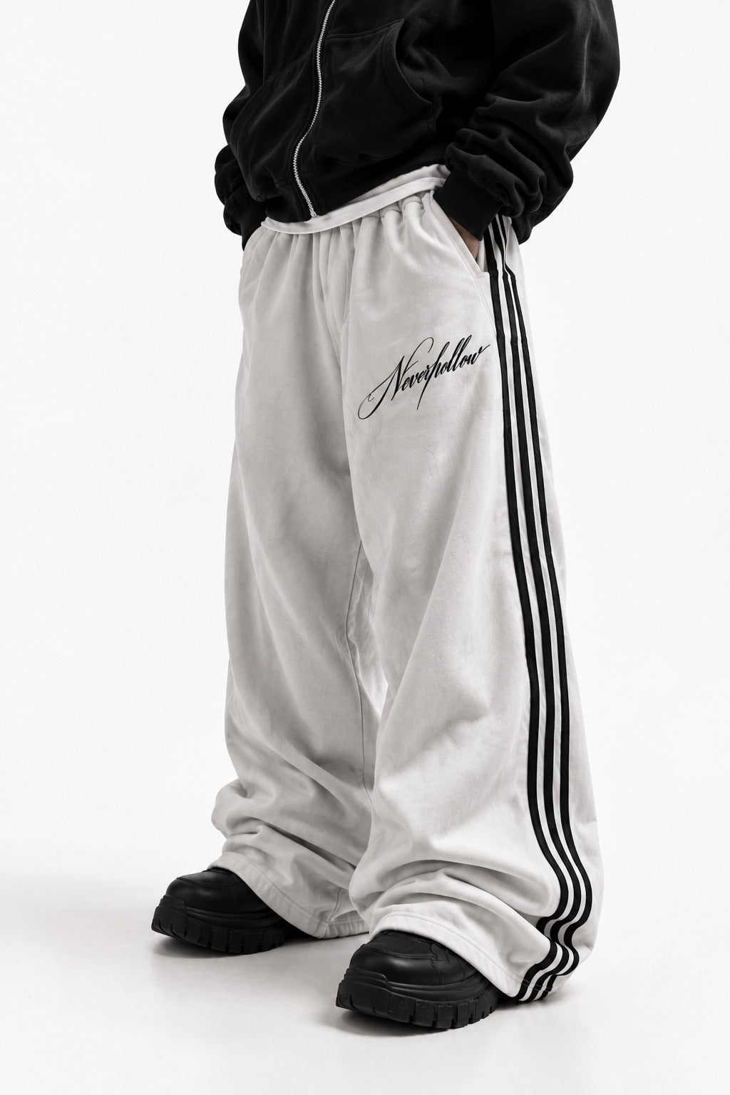 Drift Track Pants Bone, worn, front view, with black side stripes and the Neverhollow script on the front